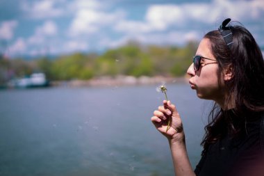 Bulutlu bir günde karahindiba üfleyen beyaz bir kız. Tasasız mutluluk kavramı.