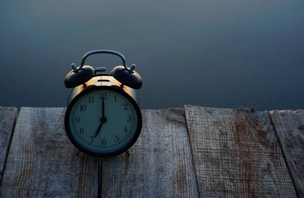 Zomertijd concept. Wekker op houten brug op zee zonsopgang achtergrond — Stockfoto