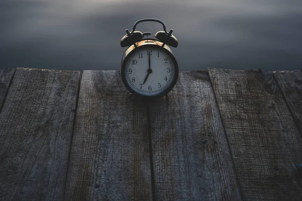 Concepto horario de verano. Reloj despertador en puente de madera sobre fondo de salida del sol del mar — Foto de Stock