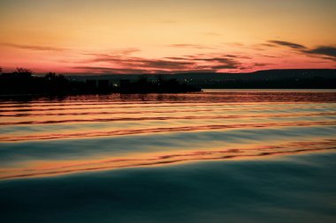 Gün batımında gölde hafif dalgalar ve sinematik renklendirme