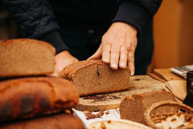 Ekmekçi adam bıçakla siyah ekmek kesiyor.