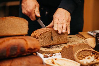Ekmekçi adam bıçakla siyah ekmek kesiyor.