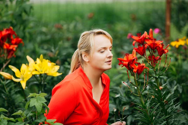 Bahçedeki Genç Kadın Kırmızı Zambak Kokluyor — Stok fotoğraf