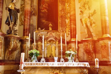 Bir Katolik kilisesinin içi - Almanya 'da bir kilisenin mihrabı. Altın dekoratif elementler, güneş ışığı altında kilise mumları..