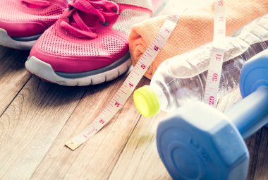 Spor ayakkabı, havlu, su, mezura ve ahşap flo üzerinde halter