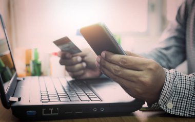 Dizüstü bilgisayar ve cep telefonu online alışveriş kullanarak iş adamı.