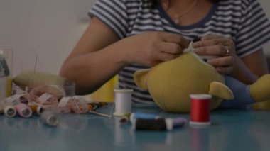 Evdeki masada oyuncak ayı bebeği diken ve tamir eden bir kadın. Ev işi. Evden çalış..