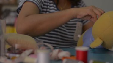 Evdeki masada oyuncak ayı bebeği diken ve tamir eden bir kadın. Ev işi. Evden çalış..