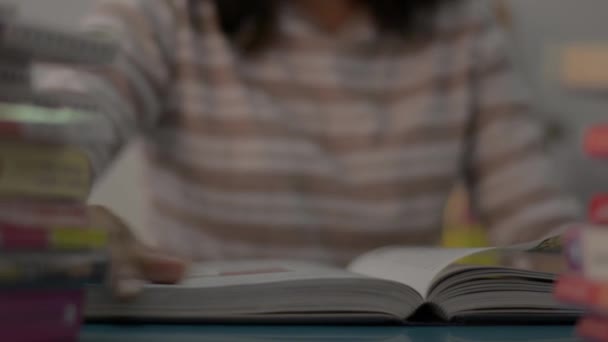 女の子はページをめくり 家のテーブルの上に本のスタックで教科書を読んでいます 教育理念 — ストック動画
