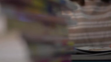 Kız sayfayı çevirir ve evdeki masanın üstünde kitap yığını olan bir ders kitabı okur. Eğitim konsepti. Döndürme çekimi.