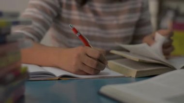 Kız evdeki masada ödev yaparken yazıyor ve okuyor. Eğitim kavramı. 