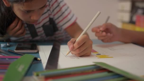 2人の女の子が紙の上に描画し お互いが自宅で机の上に宿題を行うのを助ける 教育理念 — ストック動画