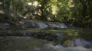 Yağmur ormanlarındaki ağaçların gölgesinin altındaki şelale manzarası. Tayland 'daki dağdan tatlı su akıyor..
