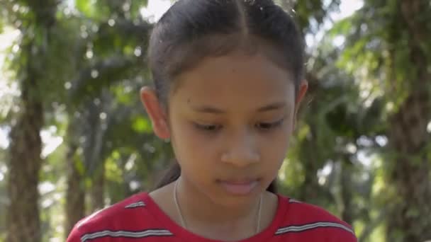 亚洲可爱的女孩在阳光下走在油棕种植园里 — 图库视频影像