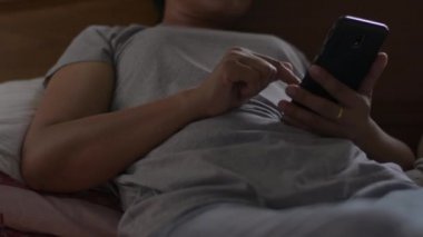 Sosyal güvenlik için cep telefonu kullanan kadın ellerini kapat. Yatakta akıllı telefonuyla sosyal uygulamaları kontrol eden Asyalı bir kadın. Kablosuz teknoloji kavramı.
