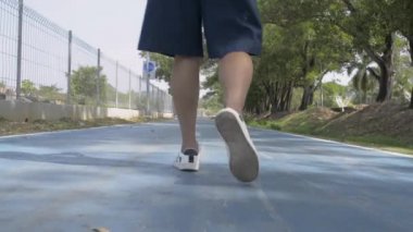 Hasır şapka takan Asyalı kadının arkadan görünüşü yaz boyunca halk parkında yürüyor..