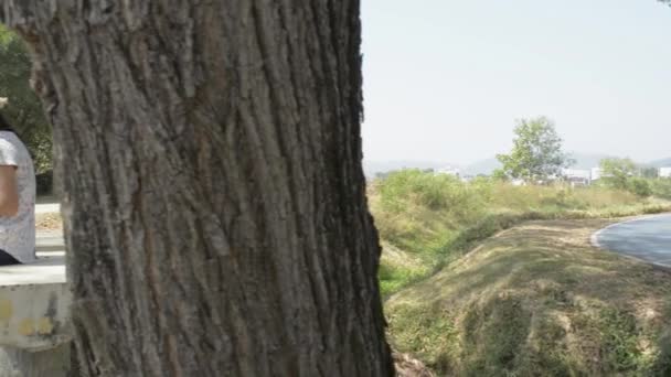 Ασιάτισσα Γυναίκα Casual Φόρεμα Κάθεται Κάτω Από Δέντρο Και Χρησιμοποιώντας — Αρχείο Βίντεο