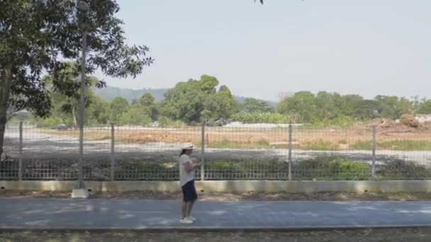 Азиатка Повседневной Одежде Ходит Дороге Пользуясь Мобильным Телефоном Общественном Парке — стоковое видео
