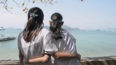 Mother and her daughter watching the beautiful scenery of the pier in phuket. Expression of love between mother and daughter.