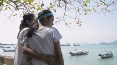Mother and her daughter watching the beautiful scenery of the pier in phuket. Expression of love between mother and daughter.