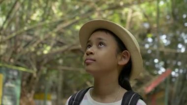 Asian cute girl with backpack looking around in the jungle at natural park camp in thailand.