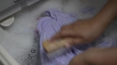 Kadının elleri çamaşır sepetini yıkarken çamaşırları temizlemek için fırçalıyor..