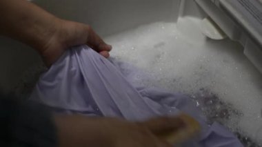 Kadının elleri çamaşır sepetini yıkarken çamaşırları temizlemek için fırçalıyor..