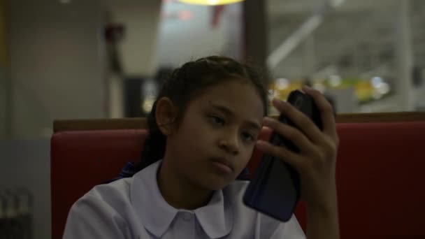午餐后 亚洲可爱的女学生坐在餐厅里用手机 — 图库视频影像