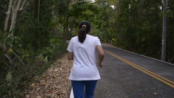 亚洲女人在路上穿过小山 从女性赛跑选手的后方看 目标是热带森林中的高山 慢动作 — 图库视频影像