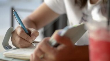 Asyalı bir kadın oturmuş günlüğe bir bardak meyve suyuyla içki dükkanında hayata ilham vermek için bir şeyler yazıyor..
