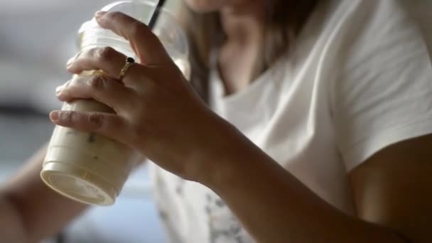 コーヒーショップで冷たい飲み物を飲んでいる間に通信し オンラインで社会的なチャットのための携帯電話上で使用し テキストメッセージアジアの女性 — ストック動画