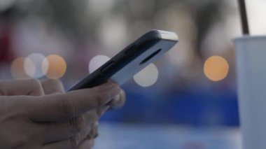 Cep telefonuyla iletişim kurmak ve sosyal medyada geceleri sohbet etmek için cep telefonuna mesaj atan bir kadının elleri. Gece piyasası ışıklandırma bokeh arkaplan.