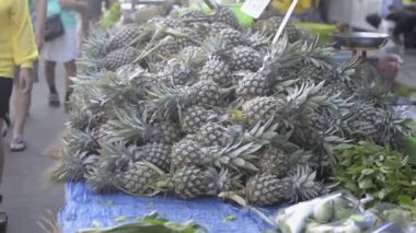 Ananas yığını sabah pazarında satılıyor. Pofet 'te çiftçi pazarında yürüyen insanlarla tarım ürünleri satılıyor..
