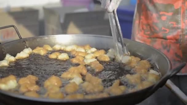 밀가루를 튀기고 길거리 시장에서 기름에 반죽을 박는다 — 비디오