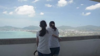 Genç kız, yaz boyunca Phuket 'teki manzara kulesinde ayakta durup körfezin güzel manzarasını izlerken annesine mutlu bir şekilde sarılıyor. Aşkın ifadesi.
