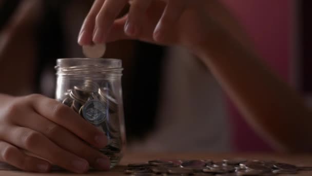 将来の費用のためにガラス瓶にお金を入れてカジュアルなドレスの女の子 お金の概念を — ストック動画