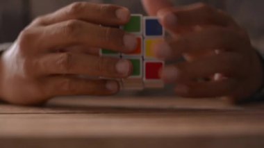 Masadaki Rubik küp bulmacasını çözen iş adamının ellerini kapat. İş kavramında problem çözme.