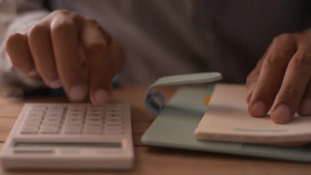机の上で経費を計算する男の手を閉じてください お金や保険の概念を節約 — ストック動画