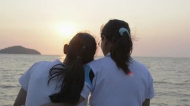 Annesinin kızına mutlu bir şekilde sarılıp, deniz manzarasının keyfini çıkarırken Pofet 'te güneşin doğuşunu seyretmesi. Tayland. Yavaş çekim.