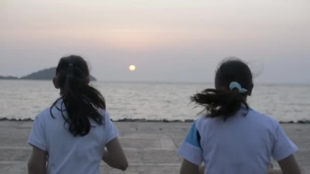 母親と娘が一緒に海岸にジョギングし プーケットで日の出の間に腕を空気中に上げの背面ビュー スローモーション — ストック動画