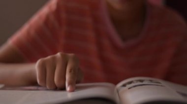Kitap okuyan küçük bir kız. Bayan öğrenci okurken parmaklarını sayfa boyunca hareket ettiriyor. Eğitim kavramı.