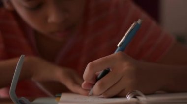 Not defterine yazan küçük bir kızın elini kapat. Okul çocuğu bir günlüğe not alıyor. Yazı malzemeleriyle ödev yapıyorum. Eğitim kavramı.