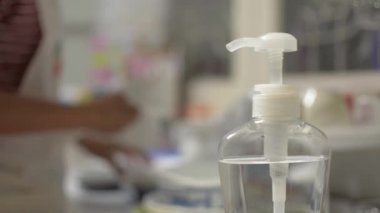 COVID-19 salgını sırasında ellerini alkol jeliyle yıkayan bir kadın. Ev hanımı virüs yayılmasını önlemek için mutfak malzemelerini temizliyor. Coronavirus koruması. 