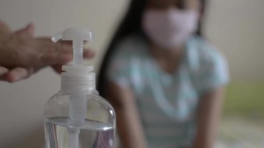 Anne ellerini alkol jeliyle temizliyor ve yaklaşmadan önce koruyucu maske takıyor ve COVID-19 salgını sırasında kızının saçını tarıyor. Coronavirus koruması. 