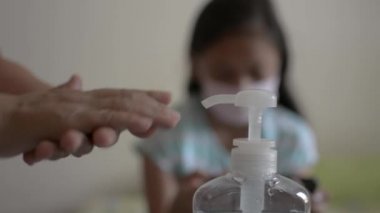 Anne ellerini alkol jeliyle temizliyor ve yaklaşmadan önce koruyucu maske takıyor ve COVID-19 salgını sırasında kızının saçını tarıyor. Coronavirus koruması. 