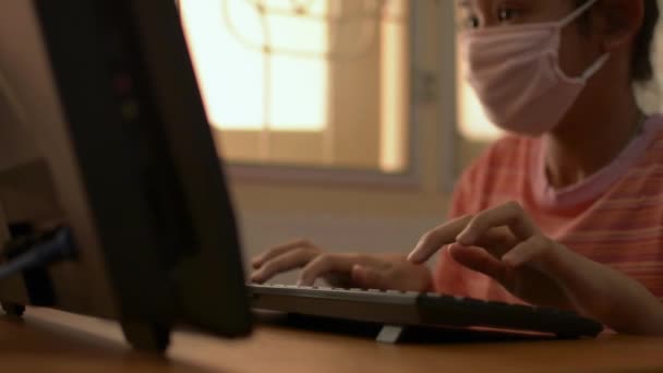 在Covid 19疫情爆发期间 带着防护面具的可爱女孩在家里的办公桌上与电脑一起工作 专心听我说家庭概念研究 — 图库视频影像