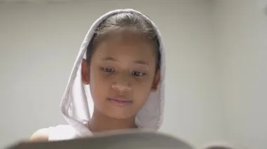 Kütüphanede kitap okuyan, beyaz kapüşonlu tişörtlü, sevimli, genç bir kız. Güzel bayan genç, kitaplardan faydalı bilgiler ve bilgiler edinmeyi sever. Eğitim kavramı.