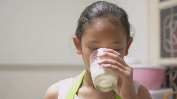 牛乳を飲みながら舌で嬉々と舌を舐めながらエプロンに身を包んだ健康な可愛い女の子をポートレート 健康と栄養の概念 — ストック動画