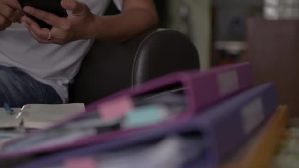 在Covid 19疫情爆发期间 身穿休闲装的妇女坐在皮革沙发上 使用手机 在家里处理一堆文件 从家里工作的概念 潘宁铅球 — 图库视频影像