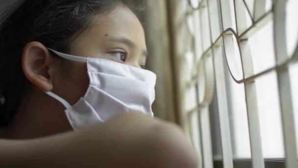 Chica Adorable Asiática Con Máscara Protectora Mirando Por Ventana Desesperadamente — Vídeos de Stock